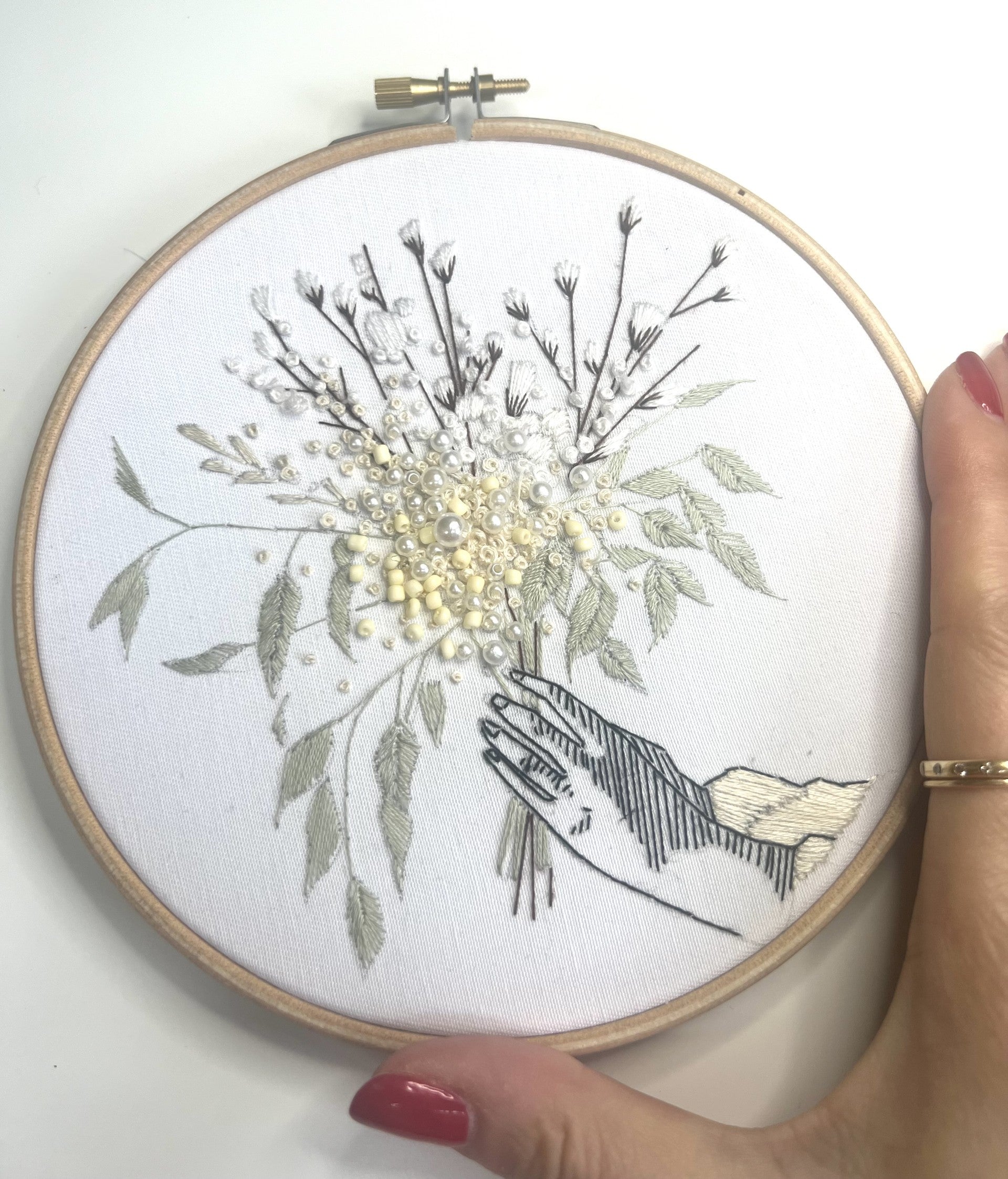 white foral embroidery pattern with hand for scale